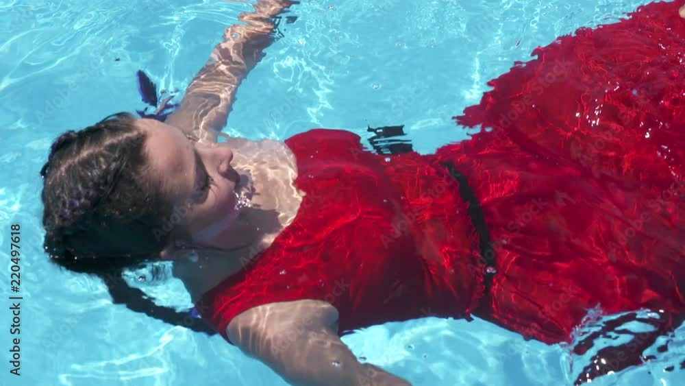 red dress pool Young Woman Floating on Swimming Pool in Red Dress. Beauty Shot Stock Image