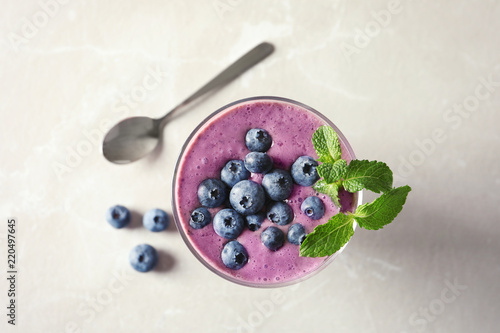 Glass with blueberry smoothie on light background, top view