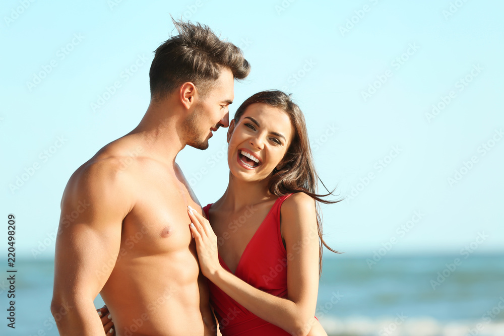 Happy young couple posing near sea on beach Happy young couple posing near sea on beach