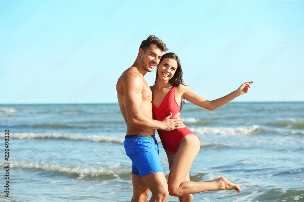 Happy young couple posing near sea on beach Happy young couple posing near sea on beach