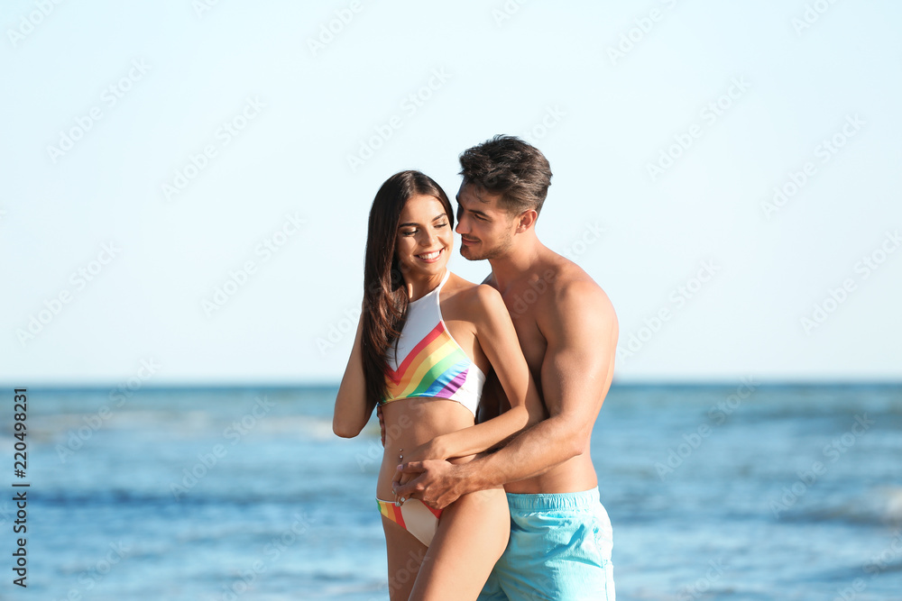 Happy young couple posing near sea on beach Happy young couple posing near sea on beach