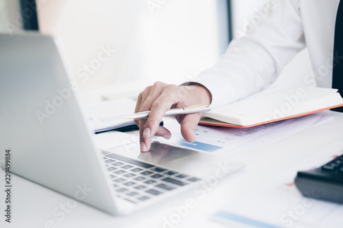 Businessman analyzing investment charts by using his laptop and calculator in modern office, Business and Office concept.