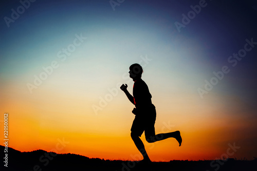 Fototapeta Naklejka Na Ścianę i Meble -  silhouette of man running outdoor cross-country at sunset