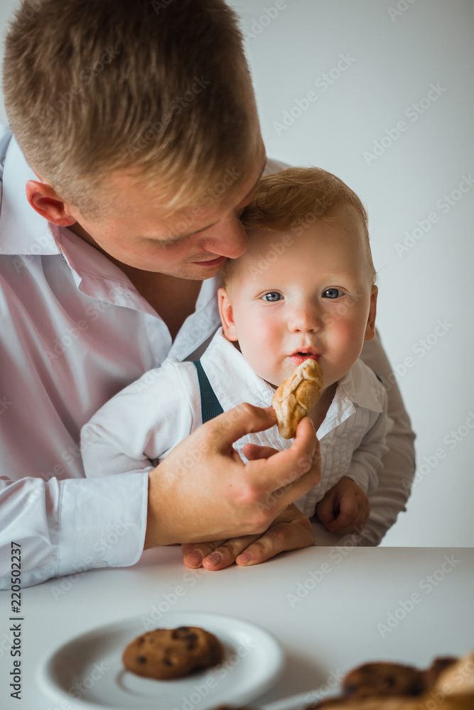 Dad feeds his young son a croissant. father and his son having a delicious breakfast together. Dad feeds his young son a croissant. father and his son having a delicious breakfast together.