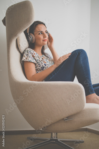 Принти на полотні Pretty, young woman listening to her favorite music on hi-fi headphones sitting