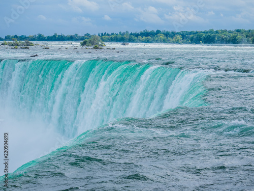 It is a Niagara Falls on the border of Canada and the United States. Splashes are greatly rising due to abundant water volume.