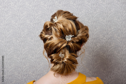Female hairstyle is a low bunch on the head of a brown-haired woman.