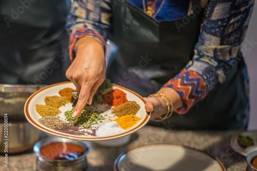 Woman in kitchen pointing out South Asian spices