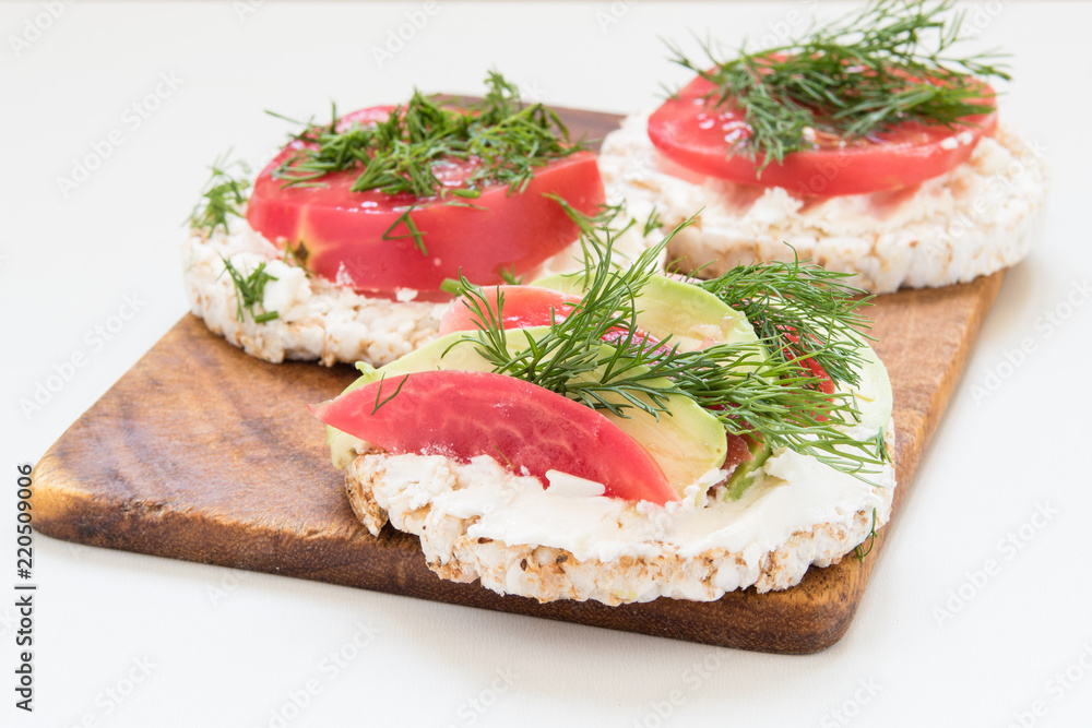 round crisp breads with cheese, tomatoes and avocado on a cutting board round crisp breads with cheese, tomatoes and avocado on a cutting board