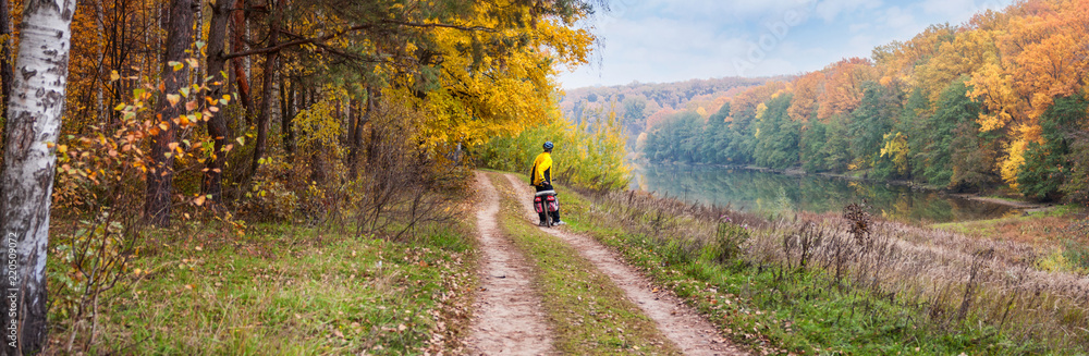 Autumn landscape, panorama, banner - the road with cyclist near lake in the sunny day