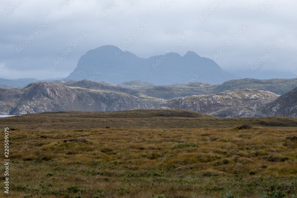 View of the Scottish Highlands near Lochinver, showing Mount Suilven in the background and heather in the foreground. 