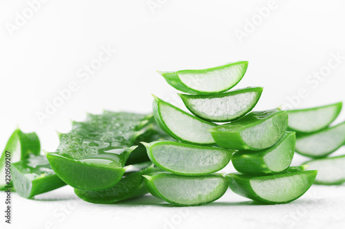 Aloe vera leaf with water droplets on white background.