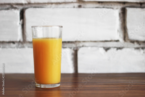 freshly squeezed orange juice glass on brick wall background in loft style