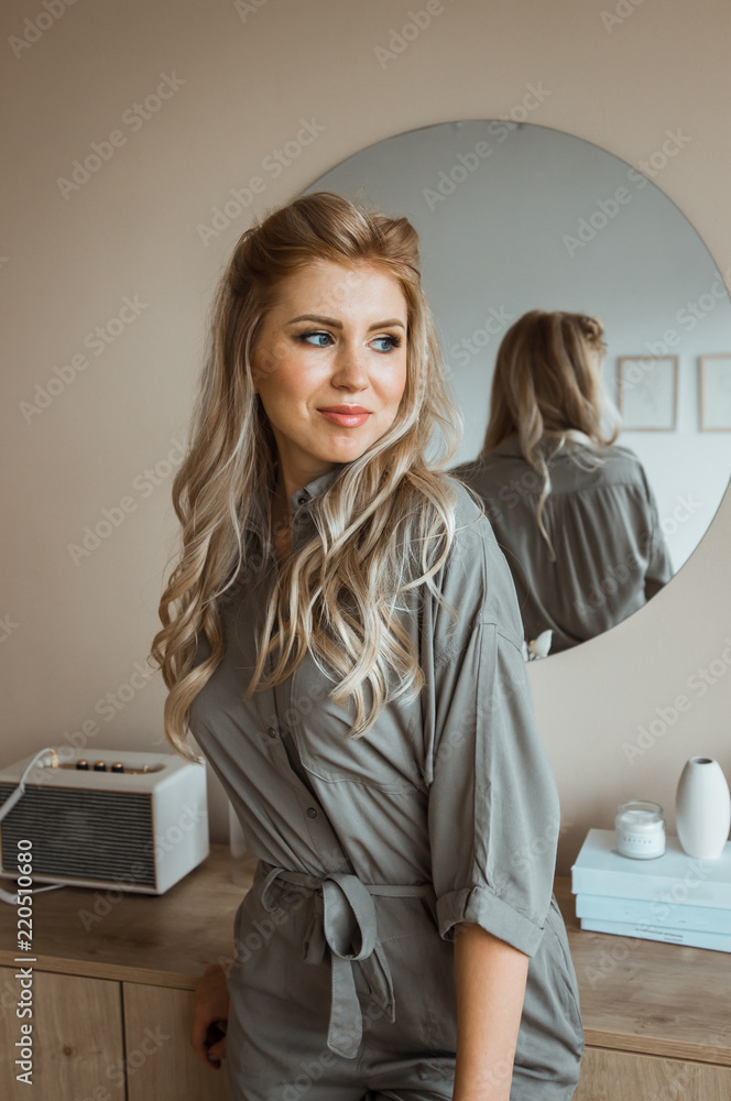 Yong girl in a gray suit near the mirror