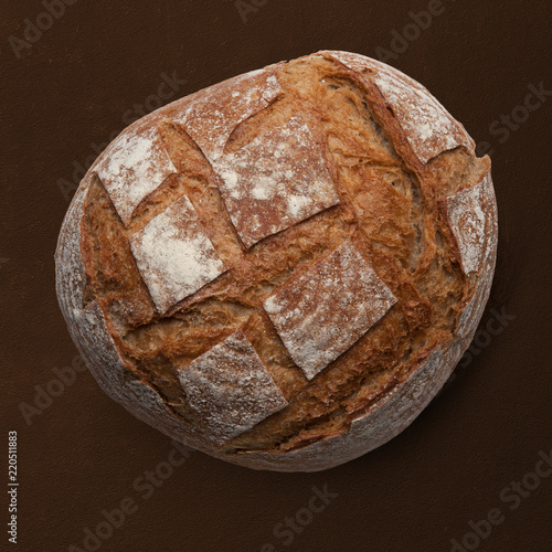 A loaf of rye bread on a brown background. View from above