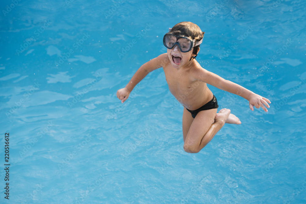 Kid playing and jumping in the pool