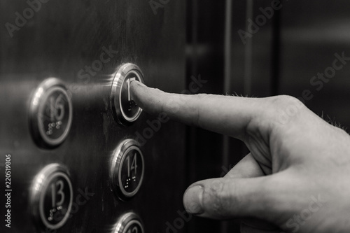 the man presses the elevator button. black and white.