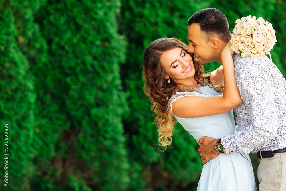 the guy gently kisses his girlfriend who closed her eyes and bend back against the background of green trees