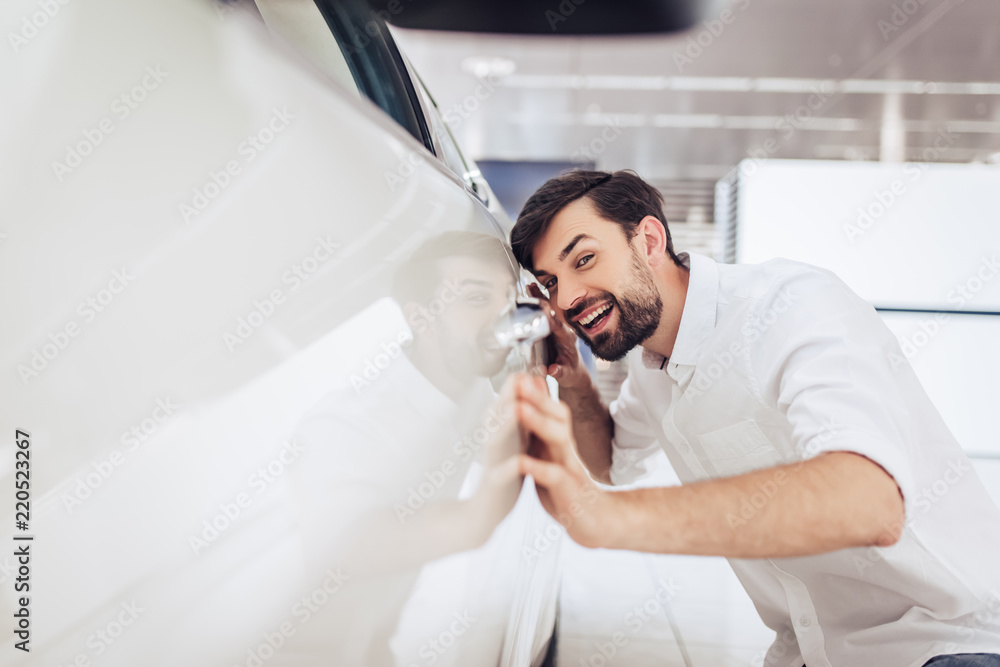 man looking at new car in dealership salon man looking at new car in dealership salon