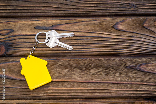 keys, keychain in the form of a house on the background of a wooden table. real estate, housing. purchase, sale.