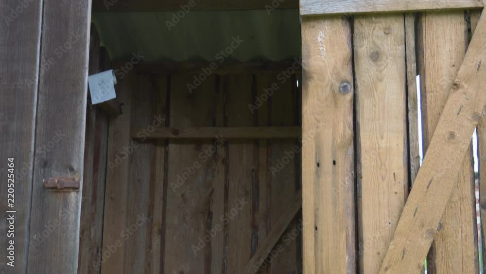 The wooden door of the outhouse toilet latrine with the roof and some closet inside