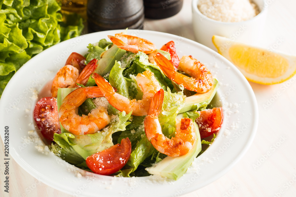 Fresh Caesar shrimp salad with delicious prawns, ruccola, spinach, cabbage, arugula, egg, parmesan and cherry tomato on wooden background. Oil, salt and pepper. Healthy and diet food concept. Fresh Caesar shrimp salad with delicious prawns, ruccola, spinach, cabbage, arugula, egg, parmesan and cherry tomato on wooden background. Oil, salt and pepper. Healthy and diet food concept.