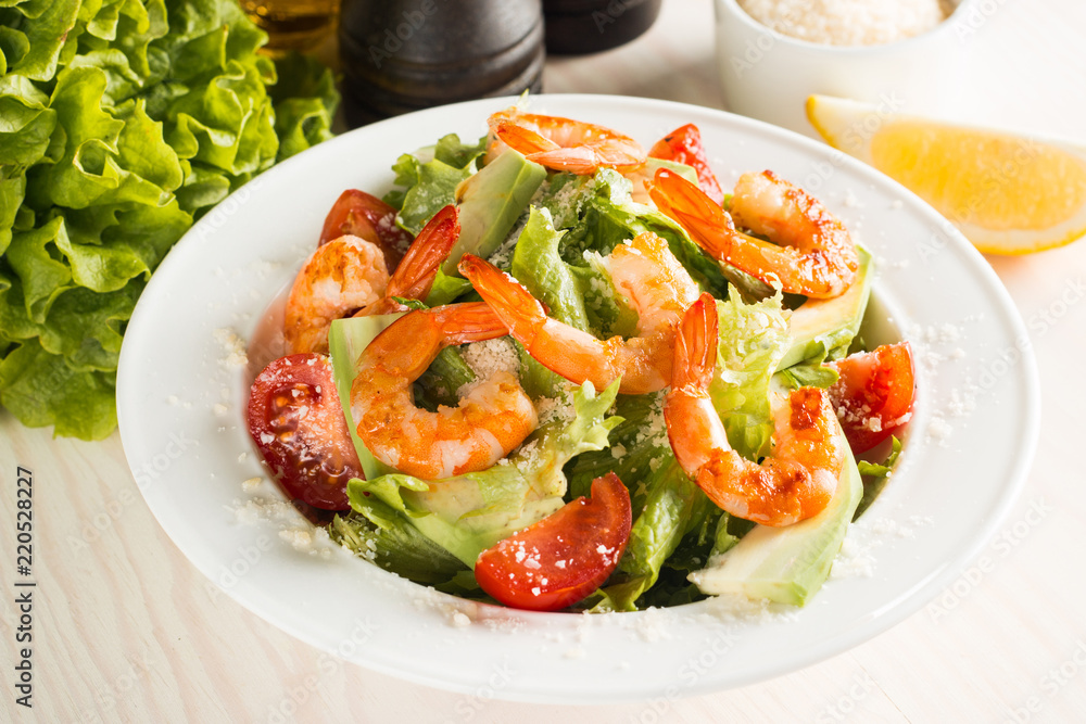 Fresh Caesar shrimp salad with delicious prawns, ruccola, spinach, cabbage, arugula, egg, parmesan and cherry tomato on wooden background. Oil, salt and pepper. Healthy and diet food concept. Fresh Caesar shrimp salad with delicious prawns, ruccola, spinach, cabbage, arugula, egg, parmesan and cherry tomato on wooden background. Oil, salt and pepper. Healthy and diet food concept.