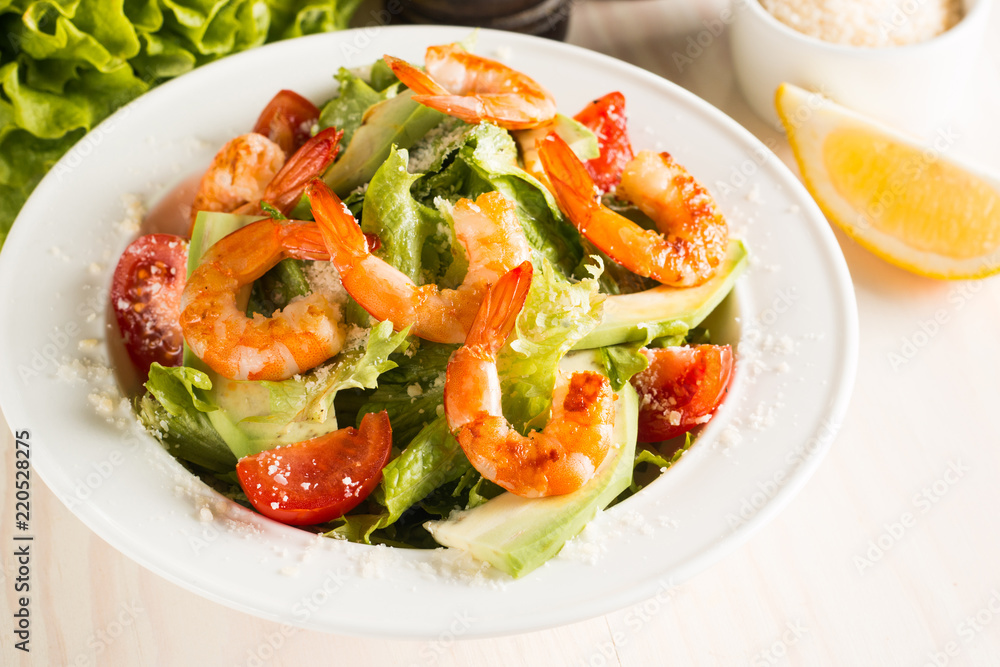Fresh Caesar shrimp salad with delicious prawns, ruccola, spinach, cabbage, arugula, egg, parmesan and cherry tomato on wooden background. Oil, salt and pepper. Healthy and diet food concept. Fresh Caesar shrimp salad with delicious prawns, ruccola, spinach, cabbage, arugula, egg, parmesan and cherry tomato on wooden background. Oil, salt and pepper. Healthy and diet food concept.