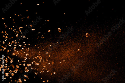 Split debris of brown stone exploding against black background. photo