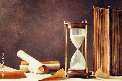 Sand running through the hourglass and old vintage books. Time keeper concept. photo