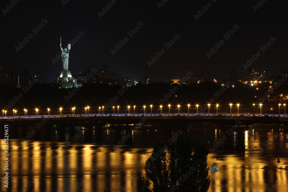 cityscape on the background of a bridge and a river with a beautifully lit statue