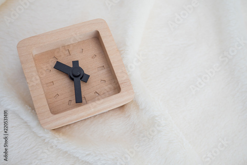 Wooden square clock on white fablic background photo