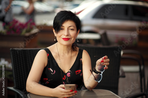 stylish short-cut blackhaired woman waiting at a table in cafe restaurant photo