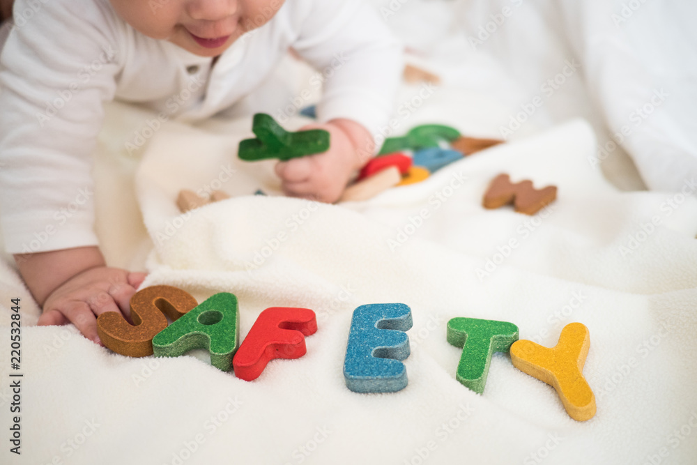 Safety text wooden word on blanket with blurred kid and copy space background Safety text wooden word on blanket with blurred kid and copy space background
