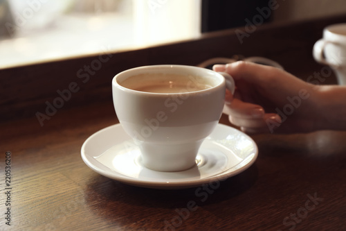 Woman with cup of fresh aromatic coffee at table