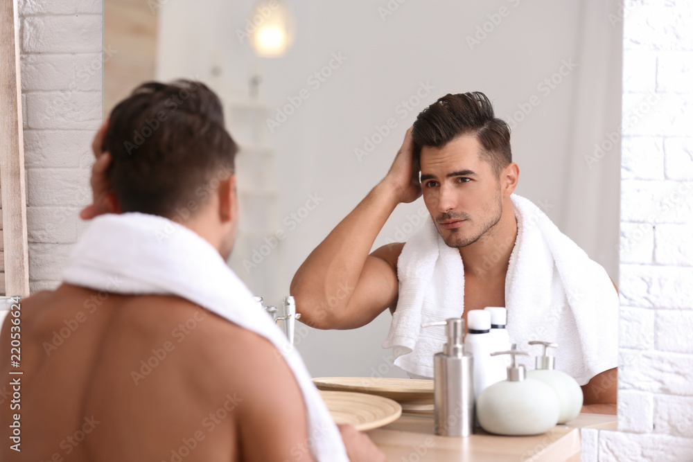 Fototapeta premium Young man with stubble ready for shaving near mirror in bathroom