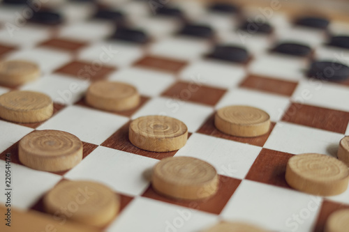 This is a wooden checkers board with black and white pawns game setup ready to play a