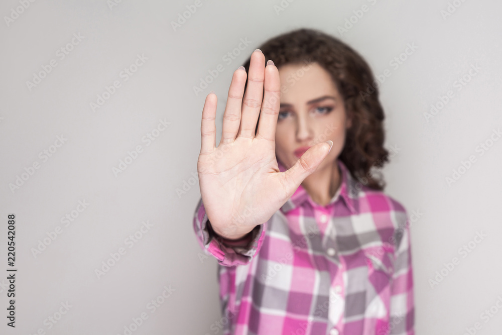 Stop it. serious unhappy girl with pink checkered shirt, curly hairstyle and makeup standing, looking at camera with ban rejection or stop warning. indoor studio shot, isolated on gray background. Stop it. serious unhappy girl with pink checkered shirt, curly hairstyle and makeup standing, looking at camera with ban rejection or stop warning. indoor studio shot, isolated on gray background.