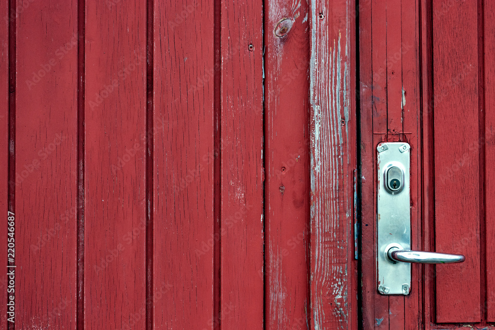 red door against a red wall. Door has a stainless handle and lock red door against a red wall. Door has a stainless handle and lock