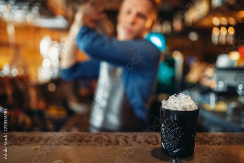 Fototapeta Naklejka Na Ścianę i Meble -  Black glass full of ice stands on bar counter