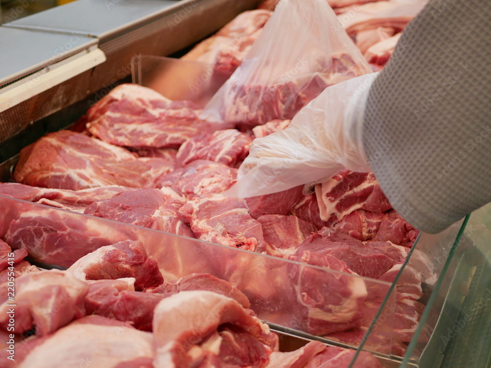 Pieces of pork in tray for sale being selected / picked by a customer - do-it-yourself retail butchery