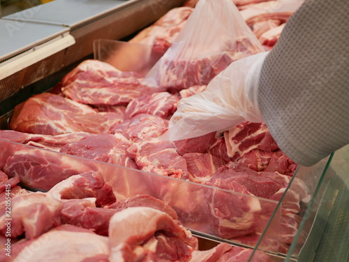Pieces of pork in tray for sale being selected / picked by a customer - do-it-yourself retail butchery