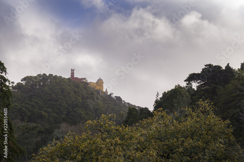 Pena Palace on green hill in forest in Sintra, Portugal with clouds