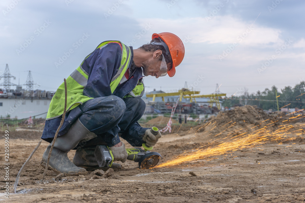 Worker cuts metal with angle grinder