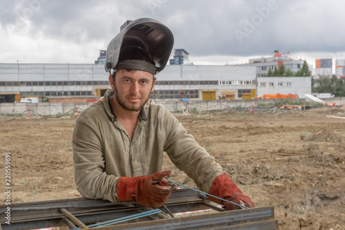 Welder at the construction site makes a metal construction photo