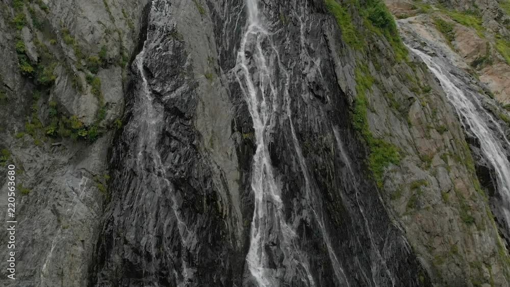 Tracking and top shot Air shot from a stream of water splashing waterfall on a rock wall in the Caucasus Mountains. Around the jet of the waterfall Tracking and top shot Air shot from a stream of water splashing waterfall on a rock wall in the Caucasus Mountains. Around the jet of the waterfall
