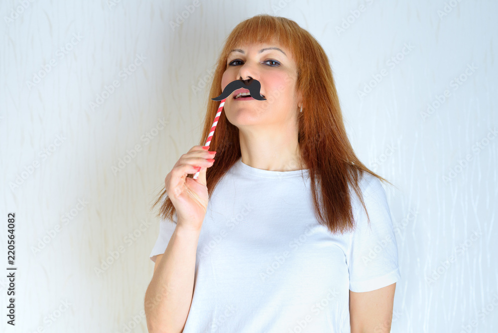 Attractive happy middle aged woman having fun with a fake moustache on stick. Senior female in period menopause. Lifestyle, Women's Health concept : playful mature ready for party. Impostor syndrome Attractive happy middle aged woman having fun with a fake moustache on stick. Senior female in period menopause. Lifestyle, Women's Health concept : playful mature ready for party. Impostor syndrome
