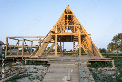 Wood frame residential building under construction. New residential construction home framing against a blue sky at sunset.