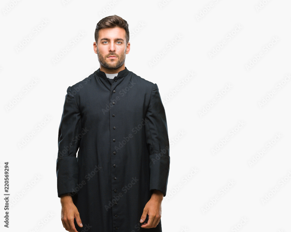 Fototapeta premium Young catholic christian priest man over isolated background with serious expression on face. Simple and natural looking at the camera.