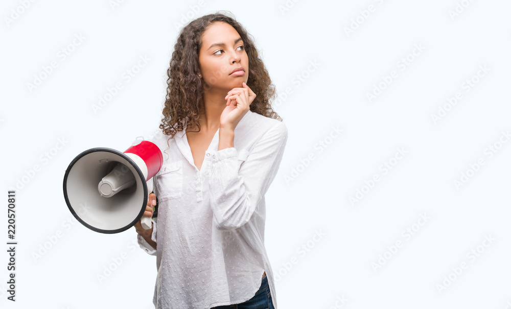 Young hispanic woman holding megaphone serious face thinking about question, very confused idea Young hispanic woman holding megaphone serious face thinking about question, very confused idea